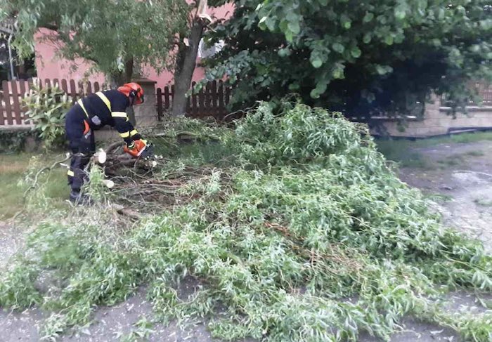 Hasič odstraňuje spadaný strom